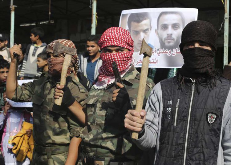 Los palestinos enmascarados sostienen hachas y un arma mientras celebran con otros una masacre en una sinagoga de Jerusalém, en Rafah, en el sur de la Franja de Gaza, el 18 de noviembre de 2014. Foto: Reuters / Ibraheem Abu Mustafa