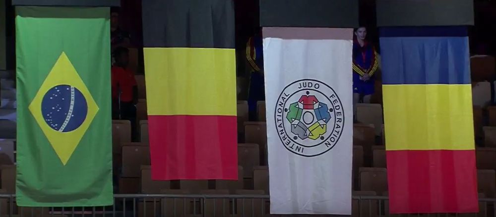 Las banderas nacionales de los ganadores de medallas en el Grand Slam de Judo 2017 en Abu Dhabi, con la bandera israelí reemplazada por la bandera de la Federación Internacional de Judo (segunda desde la derecha) debido a la prohibición de la Federación de Judo de los Emiratos Árabes sobre símbolos israelíes en el evento. La israelí Gili Cohen se llevó el bronce en la competencia, que tuvo lugar el 26 de octubre de 2017. Las otras banderas, de izquierda a derecha, son de Brasil, Bélgica y Rumania. (Captura de pantalla de YouTube)