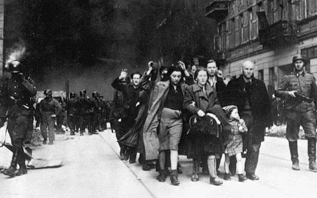 Los judíos en el Gueto de Varsovia son conducidos por soldados alemanes a un punto de reunión para su deportación a los campos de exterminio, 1943. (Dominio público)