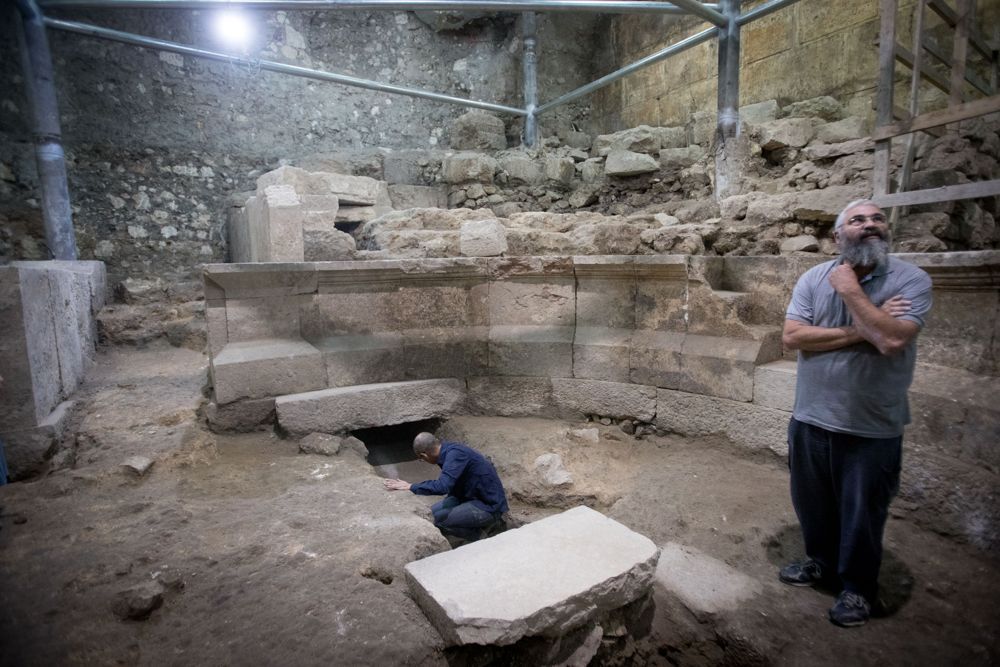 Mientras el arqueólogo Avi Salomón observa, Joe Uziel (L), arqueólogo de la Autoridad de la Antigüedad de Israeñ, limpia piedras en el sitio de una antigua estructura romana parecida a un teatro que estuvo escondida durante 1,700 años en los túneles del Muro Occidental debajo de la Ciudad Vieja de Jerusalén en octubre 16, 2017. (Yonatan Sindel / Flash 90)