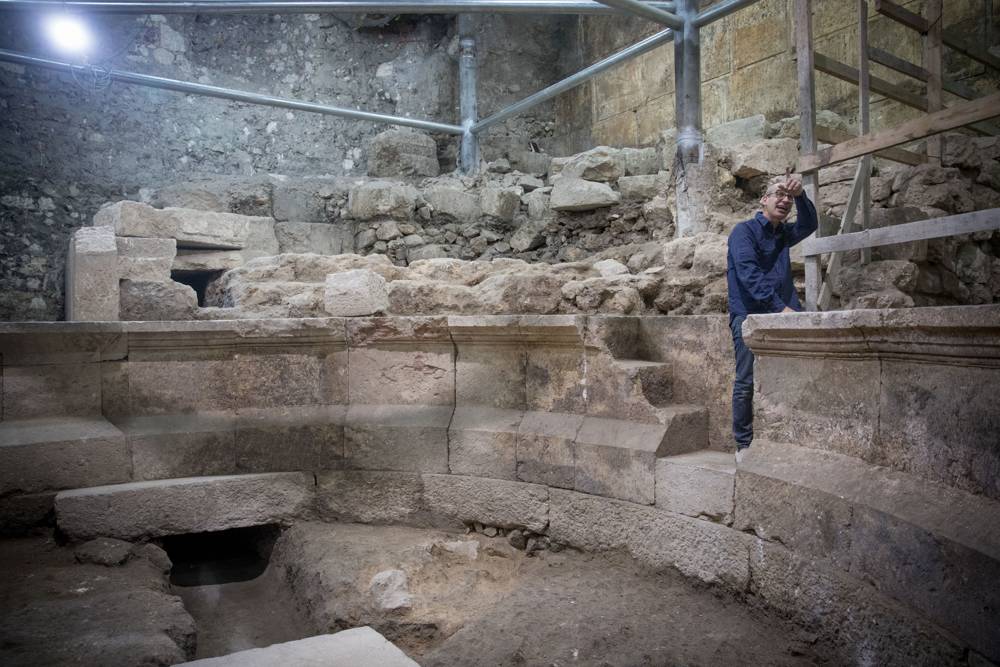Joe Uziel, arqueólogo de la Autoridad de Antigüedades de Israel, limpia piedras en el sitio de una antigua estructura romana parecida a un teatro, escondida durante 1.700 años, junto al Muro Occidental debajo de la Ciudad Vieja de Jerusalén el 16 de octubre de 2017 (Yonatan Sindel / Flash90)