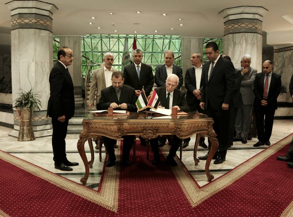 El funcionario de la Fatah, Azzam al-Ahmad, del centro a la derecha, y el representante de Hamás, Saleh al-Arouri, del centro a la izquierda, firman un acuerdo de reconciliación durante una breve ceremonia en el complejo egipcio de inteligencia en El Cairo, Egipto, el 12 de octubre de 2017. La firma del jueves se produjo después de dos días de negociaciones en la capital egipcia sobre el gobierno de la Franja de Gaza, como parte del esfuerzo más serios hasta la fecha para poner fin a la ruptura de 10 años entre los grupos árabes rivales. (AP Foto / Nariman El-Mofty)
