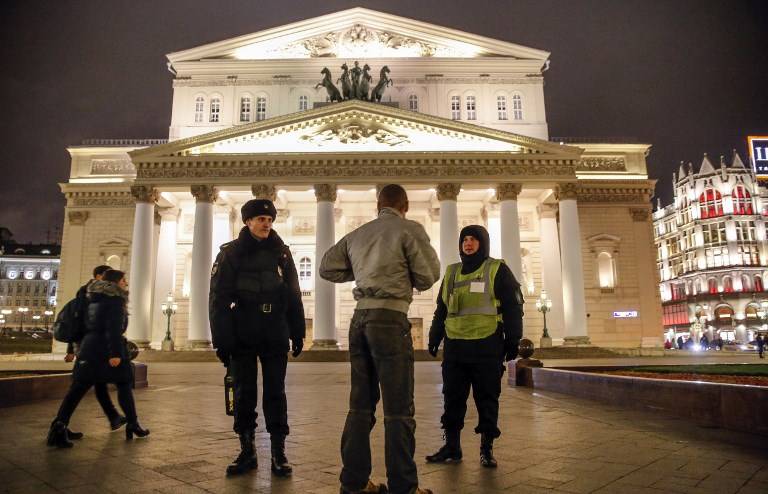 Un oficial de policía y un miembro del personal de seguridad hablan con un transeúnte mientras hacen guardia frente al Teatro Bolshoi en Moscú el 5 de noviembre de 2017. (AFP / Maxim ZMEYEV)