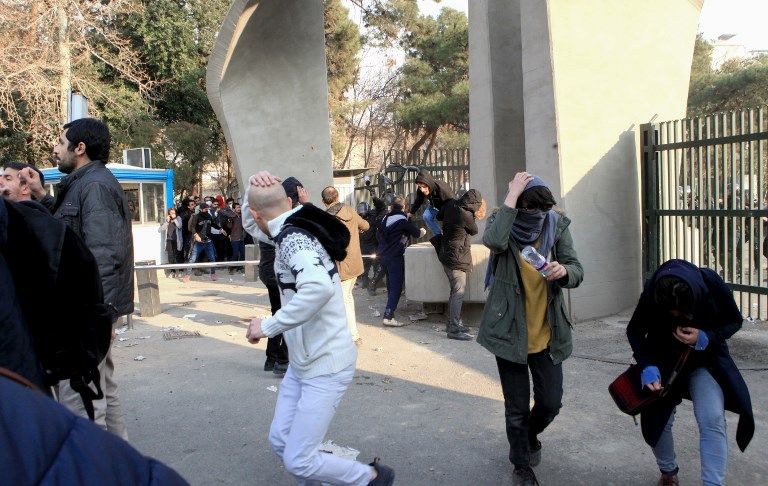 Estudiantes iraníes huyen del gas lacrimógeno en la Universidad de Teherán durante una manifestación el 30 de diciembre de 2017. (AFP PHOTO / STR)
