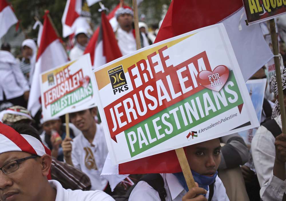 Hombres musulmanes sostienen carteles durante una manifestación frente a la embajada de Estados Unidos en Yakarta, Indonesia, en contra de la decisión del presidente estadounidense Donald Trump de reconocer a Jerusalén como la capital de Israel, 10 de diciembre de 2017. (AP Photo / Dita Alangkara)