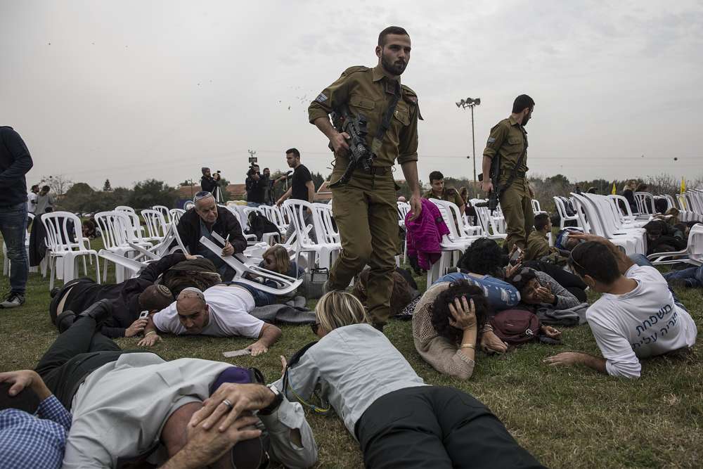 Israelíes se cubre durante una alerta de proyectil entrante en el Kibutz Kfar Aza cerca de la frontera entre Israel y Gaza, el viernes 29 de diciembre de 2017. Los israelíes se habían reunido allí para conmemorar el cumpleaños de Oron Shaul, quien fue asesinado durante la última guerra en Gaza; Hamás retiene sus restos. (AP Photo / Tsafrir Abayov)