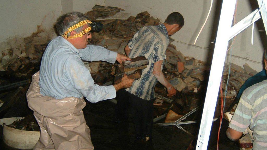 Los voluntarios intentan recuperar material de archivos judíos iraquíes del sótano inundado de Mukhabarat, cuartel general de inteligencia de Saddam Hussein, 2003. (Foto de Harold Rhode, cortesía de los Archivos Nacionales de los EE. UU.)