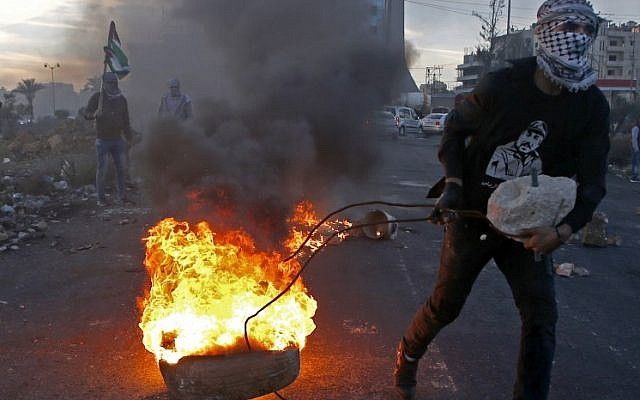 Un musulmán saca una llanta encendida durante una ola de ataques a las fuerzas de seguridad israelíes cerca de un puesto de control israelí en la ciudad de Ramallah el 9 de diciembre de 2017, luego del reconocimiento del presidente de los Estados Unidos a Jerusalén como la capital de Israel. (AFP / Abbas Momani)