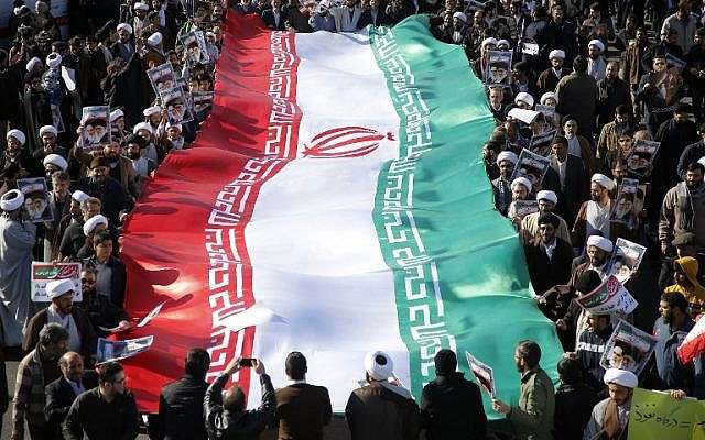 Los manifestantes progubernamentales agitan su bandera nacional durante una marcha en la ciudad de Qom, en Irán, a unos 130 kilómetros al sur de Teherán, el 3 de enero de 2018. (AFP PHOTO / Mohammad ALI MARIZAD)