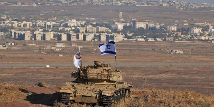 Una bandera Israelí flamea sobre los restos de un tanque en una colina en los Altos del Golán con vistas a la frontera con Siria el 18 de octubre de 2017. (AFP Photo / Jalaa Marey)