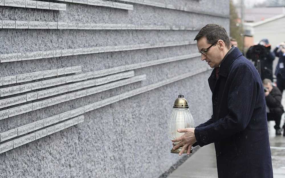 El primer ministro polaco Mateusz Morawiecki coloca una vela en una pared conmemorativa con los nombres de algunos de los polacos que salvaron judíos durante el Holocausto, en el Museo de la Familia Ulma de los polacos que salvaron judíos durante la Segunda Guerra Mundial, en Markowa, Polonia, 2 de febrero de 2018. (AP / Alik Keplicz)