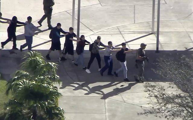 Los estudiantes de la Marjory Stoneman Douglas High School en Parkland, Fla., Evacuan la escuela luego de un tiroteo el 14 de febrero de 2018. (WPLG-TV vía AP)