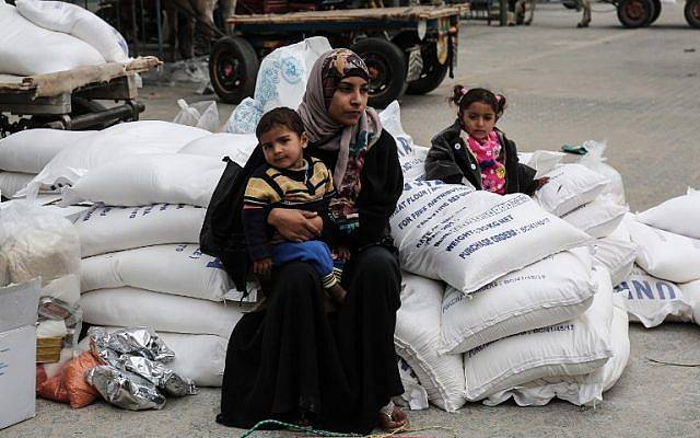 Una mujer árabe se sienta con un niño después de recibir alimentos de las oficinas de las Naciones Unidas en las oficinas de las Naciones Unidas en el llamado campo de refugiados de Khan Yunis en el sur de la Franja de Gaza el 11 de febrero de 2018, donde viven los bisnietos de los originales refugiados árabes de la guerra árabe contra Israel. (SAID KHATIB / AFP)