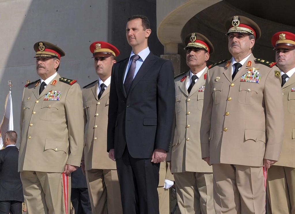 El presidente sirio Bashar Assad, centro, se encuentra junto al ministro de Defensa sirio, el general Dawoud Rajha, derecha, y el jefe de gabinete, el general Fahed al-Jasem el-Freij, izquierda, durante una ceremonia para conmemorar el 38 ° aniversario del Guerra israelí, en Damasco, Siria, en 2011. (AP Photo / SANA)