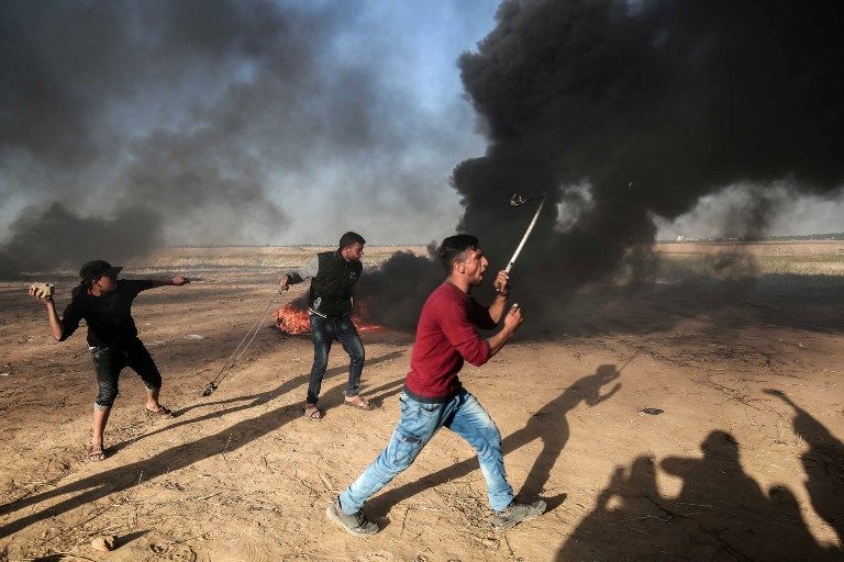 Atacantes palestinos lanzan rocas a las fuerzas de seguridad israelíes en la frontera con Israel, al este de Khan Yunis, en el sur de la Franja de Gaza, 01 de abril de 2018. (SAID KHATIB / AFP)