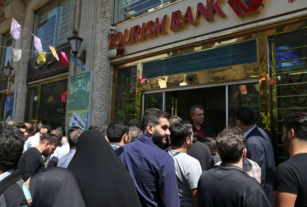 Iraníes de pie frente a un banco, con la esperanza de comprar dólares estadounidenses a la nueva tasa de cambio oficial anunciada por el gobierno, en el centro de Teherán, el 10 de abril de 2018. (Crédito: Vahid Salemi / AP)