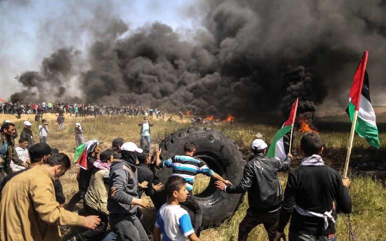 Atacantes palestinos queman neumáticos durante los enfrentamientos con las fuerzas de seguridad israelíes en la frontera de Gaza e Israel, al este de la ciudad de Gaza, el 6 de abril de 2018. (AFP PHOTO / MAHMUD HAMS)
