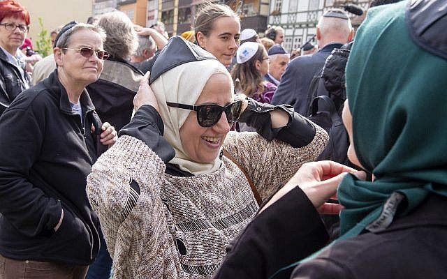 La mujer musulmana Samar Allaham, en el centro, arregla la Kipá judía en su cabeza. Además de la mujer musulmana Iman Jamous, derecha, durante una manifestación contra el antisemitismo en Alemania en Erfurt, Alemania, el 25 de abril de 2018. (AP Photo / Jens Meyer)