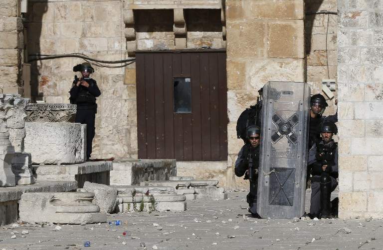 La policía israelí se cubre mientras los islamistas palestinos les arrojan piedras en el Monte del Templo de Jerusalén durante la violencia islámica por tercer día consecutivo el 28 de junio de 2016. (AFP PHOTO / AHMAD GHARABLI)