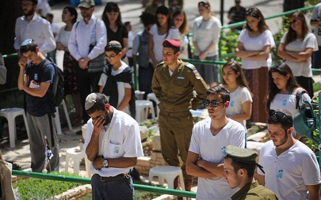 Personas en silencio junto a las tumbas de soldados israelíes en el cementerio militar de Mt Hezl en Jerusalén, mientras una sirena de dos minutos sonaba en todo Israel, conmemorando el Día de los Caídos que conmemora a los soldados caídos de Israel y las víctimas del terror el 18 de abril de 2018. (Miriam Alster / Flash 90)