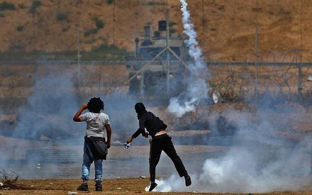 Un islamista palestino arroja un bote de gas lacrimógeno hacia las tropas israelíes cerca de Khan Younis en el sur de la Franja de Gaza, durante el quinto viernes consecutivo de violencia masiva a lo largo de la frontera entre Gaza e Israel, el 27 de abril de 2018. (AFP Photo / Said Khatib)