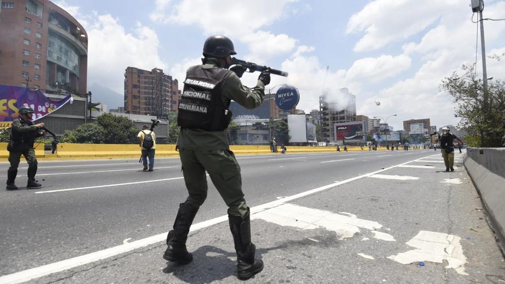 Un soldado de la Guardia Nacional apunta a un periodista con una escopeta de perdigones durante una protesta en la autopista Francisco Fajardo de Caracas. | Getty Images