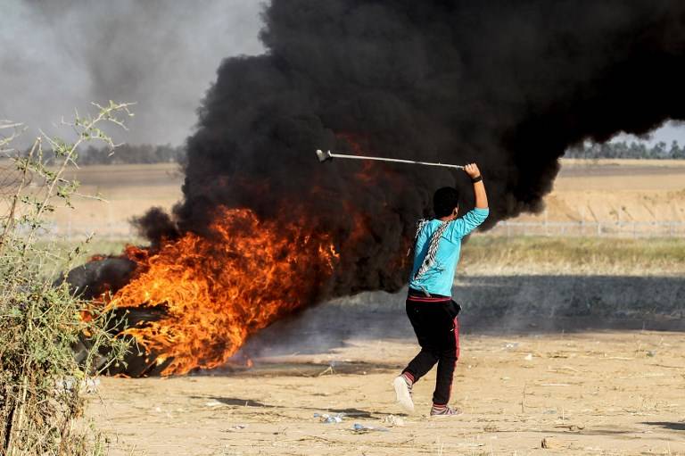 Un joven palestino lanza un honda durante los enfrentamientos después de una manifestación cerca de la frontera con Israel, al este de Khan Younis en el sur de la Franja de Gaza, el 1 de abril de 2018. (AFP PHOTO / SAID KHATIB)