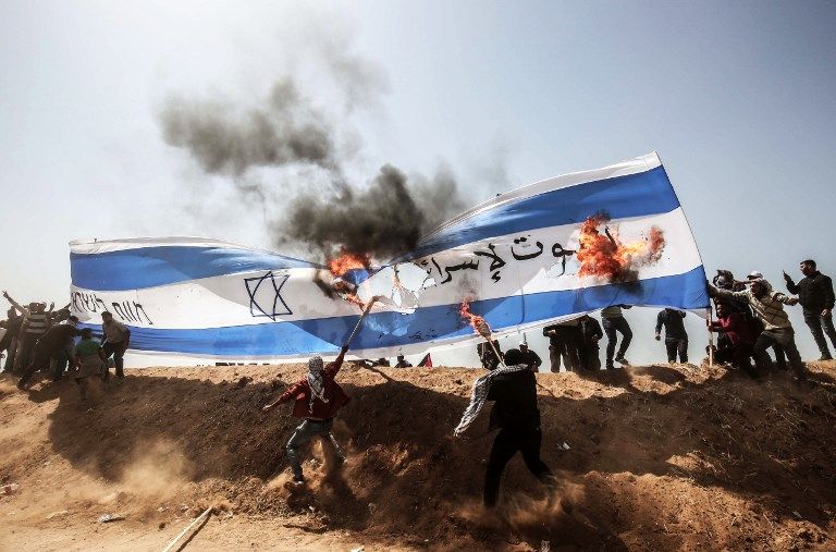 Árabes palestinos queman una bandera israelí durante los ataques islamistas contra las fuerzas de seguridad israelíes en la frontera de Gaza con Israel, al este de Khan Younis, en el sur de la Franja de Gaza el 6 de abril de 2018. (AFP PHOTO / SAID KHATIB)