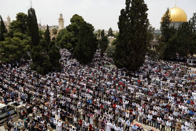 Musulmanes rezan cerca de la Cúpula de la Roca y la Mezquita Al-Aqsa, de la ocupación islámica en el Monte del Templo en Jerusalén, durante las oraciones del segundo viernes del mes sagrado del Ramadán el 25 de mayo de 2018. (AFP Photo / Ahmad Gharabli)