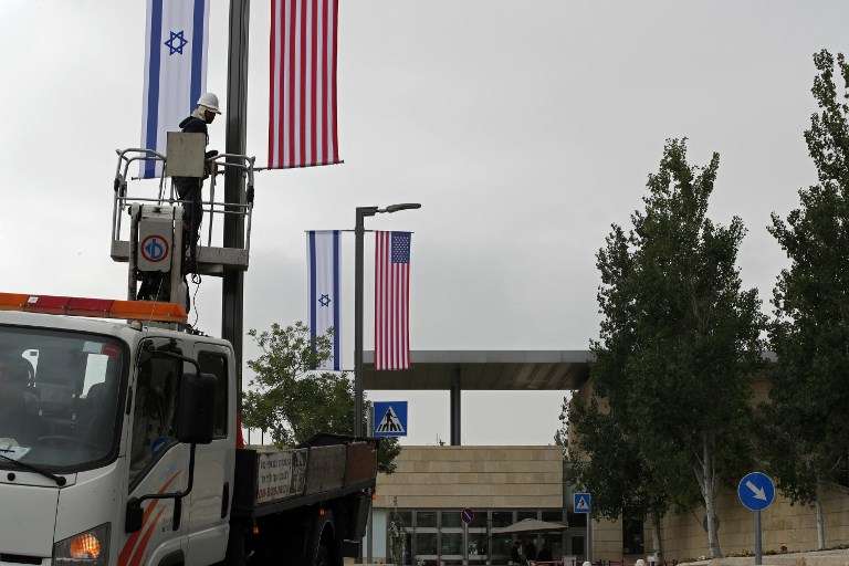 Un trabajador instala decoraciones de banderas israelíes y estadounidenses frente al actual consulado de EE. UU. en Jerusalén, donde los funcionarios estadounidenses instalarán la nueva embajada de EE. UU. el 14 de mayo. (AFP / Thomas Coex)