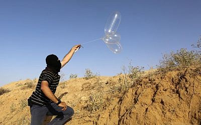 lustrativo: un palestino enmascarado lanza un globo cargado con materiales inflamables hacia Israel desde el pueblo de Rafah, al sur de Gaza, el 17 de junio de 2018. (AFP Photo / Said Khatib)