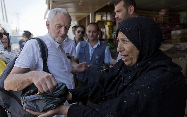Jeremy Corbyn, líder del Partido Laborista del Reino Unido, recibe dulces de la refugiada siria Sohela Sobeihi, 52 mientras hablaba con los refugiados en la carretera principal del mercado, durante su visita al campo de refugiados sirios Zaatari, en Mafraq, Jordania, el viernes 22 de junio de 2018. ( AP Photo / Nasser Nasser)