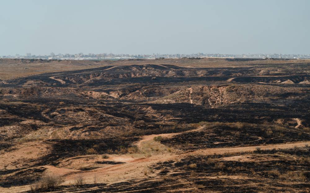 El Crater Beeri después de un incendio provocado por cometas, con Gaza en el fondo, el 6 de junio de 2018. (Luke Tress / Times of Israel)