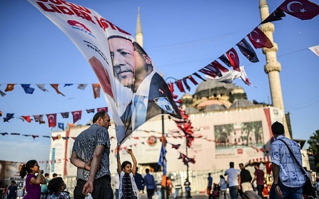 La gente camina cerca de una pancarta de campaña que muestra al presidente de Turquía en el distrito Eminonu de Estambul el 14 de junio de 2018. (AFP PHOTO / BULENT KILIC)