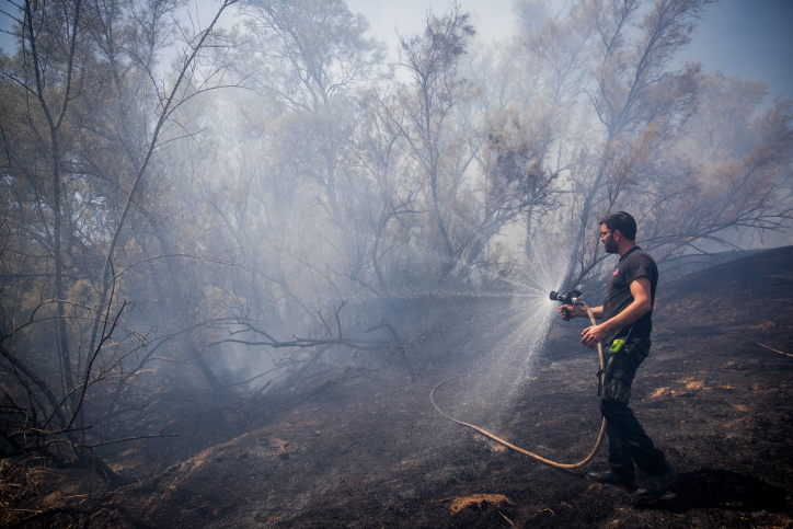 Un bombero israelí extingue un incendio en un campo causado por cometas incendiarias enviadas por palestinos a Israel desde la Franja de Gaza el 20 de junio de 2018. (Yonatan Sindel / Flash90)