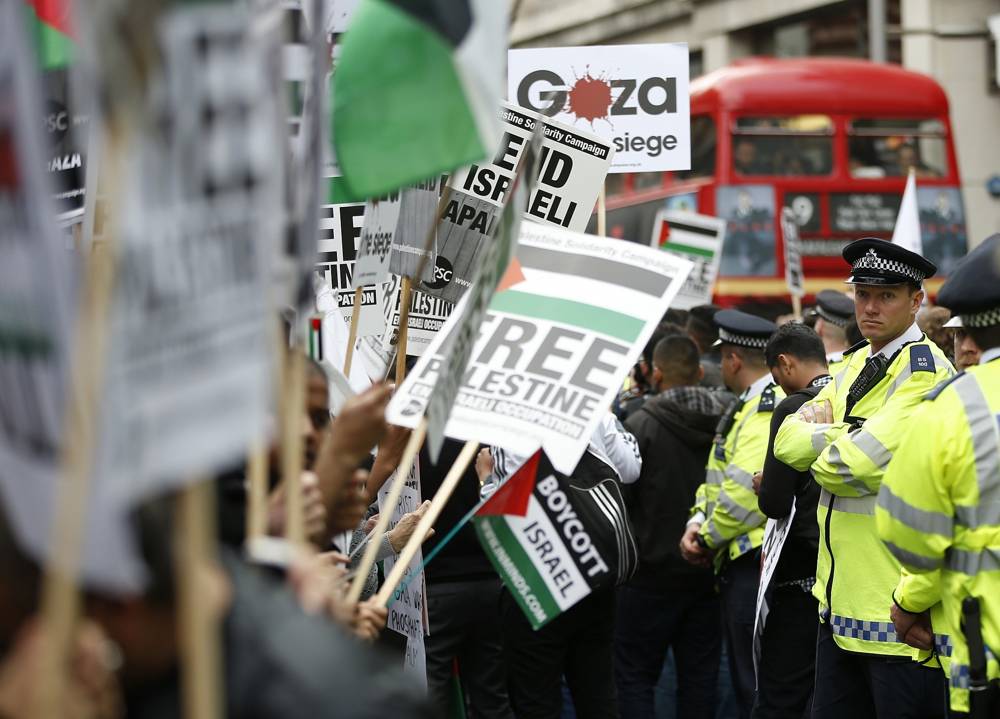 Un policía observa una línea de manifestantes cerca de la embajada de Israel protestando contra la acción tomada contra Hamás en Gaza, en Londres, el viernes 11 de julio de 2014. (AP / Alastair Grant)