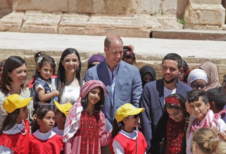 El príncipe William (C) de Gran Bretaña y el príncipe heredero jordano Hussein bin Abdullah (R) conversan con escolares sirios y jordanos durante su visita al sitio arqueológico de Jerash, el 25 de junio de 2018 (AFP PHOTO / AHMAD ABDO)