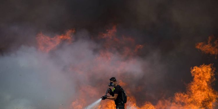 Bomberos israelíes extinguen un incendio en un campo de trigo causado por cometas voladas por manifestantes palestinos, cerca de la frontera con la Franja de Gaza, el 30 de mayo de 2018. (Yonatan Sindel / Flash90)
