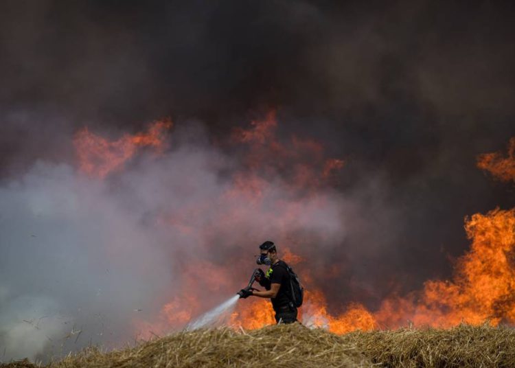 Bomberos israelíes extinguen un incendio en un campo de trigo causado por cometas voladas por manifestantes palestinos, cerca de la frontera con la Franja de Gaza, el 30 de mayo de 2018. (Yonatan Sindel / Flash90)