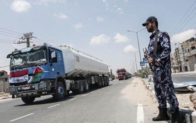 Las fuerzas de seguridad palestinas montan guardia mientras los camiones egipcios que conducen combustible conducen por una calle después de ingresar al sur de la Franja de Gaza desde Egipto a través del cruce fronterizo de Rafah el 21 de junio de 2017. (AFP Photo / Said Khatib)