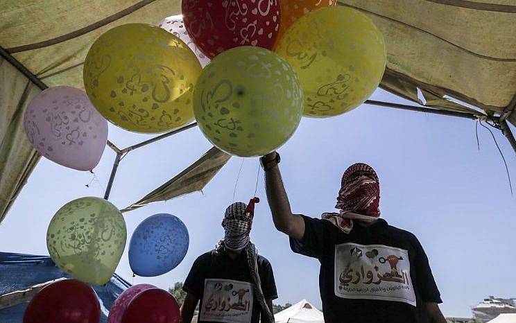 Islamistas palestinos sostienen globos antes de cargarlos con material inflamable para enviarlos hacia Israel, en la frontera entre Israel y Gaza en el centro de la Franja de Gaza el 14 de junio de 2018. (AFP PHOTO / MAHMUD HAMS)