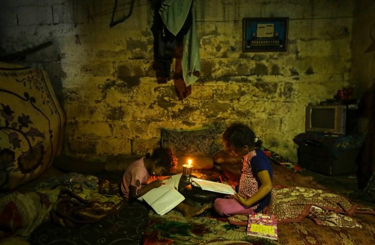 Ilustrativo: niños palestinos hacen sus deberes a la luz de las velas durante un corte de energía en la ciudad de Gaza el 11 de septiembre de 2017. (AFP Photo / Mahmud Hams)