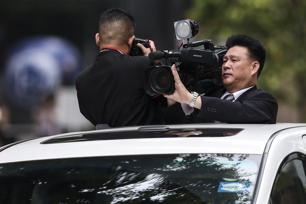 Periodistas norcoreanos filman la caravana de automóviles del líder norcoreano Kim Jong Un, cuando abandonan el hotel St. Regis en camino al Hotel Capella en Singapur, el 12 de junio de 2018, donde tuvo lugar la cumbre entre Kim y el presidente estadounidense Donald Trump. (AP Photo / Yong Teck Lim)