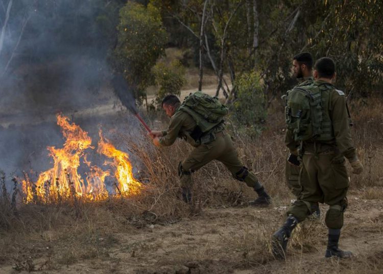 Un soldado de Israel extingue un incendio iniciado por una cometa con tela encendida lanzada por los palestinos desde Gaza el 1 de junio de 2018. (AP Photo / Tsafrir Abayov)