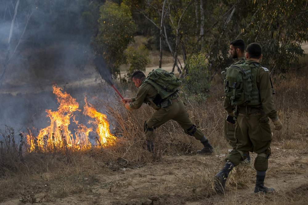 Un soldado de Israel extingue un incendio iniciado por una cometa con tela encendida lanzada por los palestinos desde Gaza el 1 de junio de 2018. (AP Photo / Tsafrir Abayov)