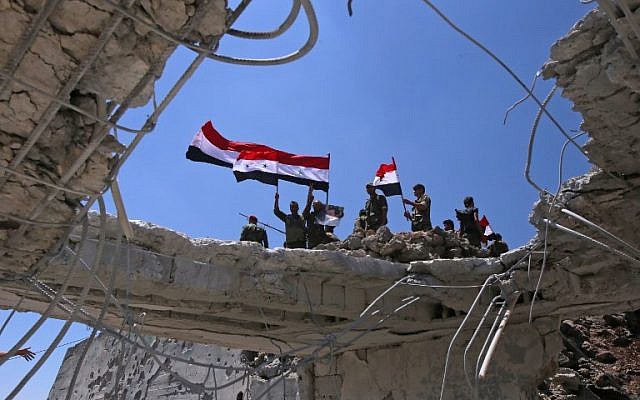 Los soldados de las fuerzas del gobierno sirio ondean sus banderas nacionales después de recuperar la ciudad de Quneitra de los rebeldes, el 19 de julio de 2018. (AFP PHOTO / Youssef KARWASHAN)