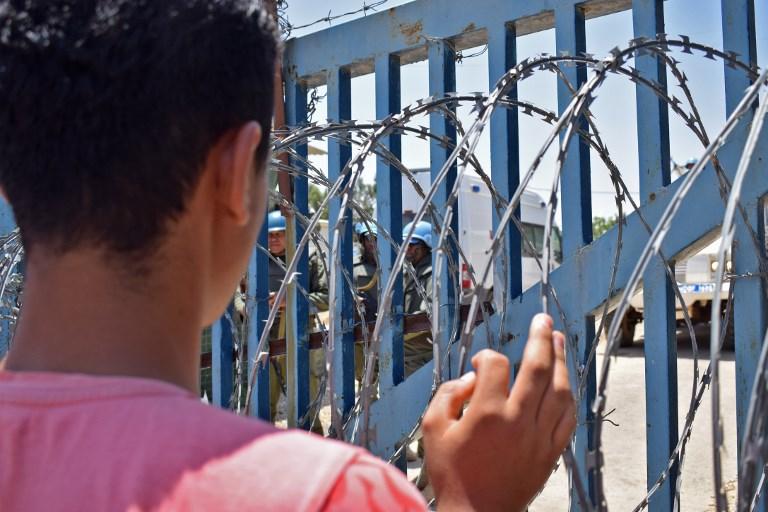 Un joven de un campamento para desplazados en la aldea siria de al-Rafid observa al personal de mantenimiento de la paz de las Naciones Unidas frente a una cerca de alambre de púas cerca de un puesto de control a lo largo de la frontera con los Altos del Golán durante una protesta contra el gobierno sirio el 4 de julio de 2018. (AFP / Jawad Abu Hamza)