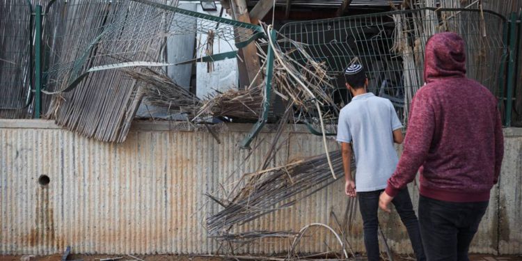 Personas en la escena en que un patio de una casa fue alcanzado por un cohete de Gaza en la ciudad de Sderot, al sur de Israel, el 14 de julio de 2018. (Hadas Parush / Flash 90)