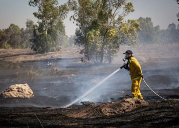 Los bomberos apagan un incendio en un campo causado por bombas incendiarias atadas a cometas voladas por los palestinos, desde la Franja de Gaza, el 27 de junio de 2018. (Flash90)