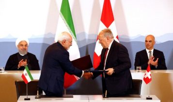 El presidente iraní Hassan Rouhani y el presidente suizo Alain Berset aplauden mientras el ministro iraní Mohammad Javad Zarif y el ministro suizo de Economía Johann Schneider-Ammann se dan la mano después de firmar un acuerdo en Berna el 3 de julio. 2018. (AFP Photo / Ruben Sprich)